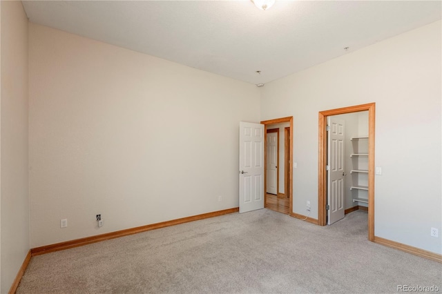 unfurnished bedroom featuring light colored carpet, a walk in closet, and a closet