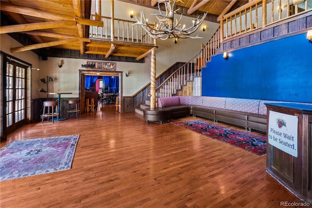 living room with hardwood / wood-style flooring, a chandelier, beam ceiling, and high vaulted ceiling