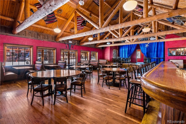 dining area with wooden ceiling, high vaulted ceiling, beamed ceiling, and hardwood / wood-style flooring