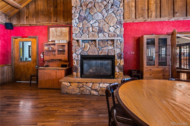 living room featuring a stone fireplace, dark hardwood / wood-style floors, beam ceiling, and high vaulted ceiling