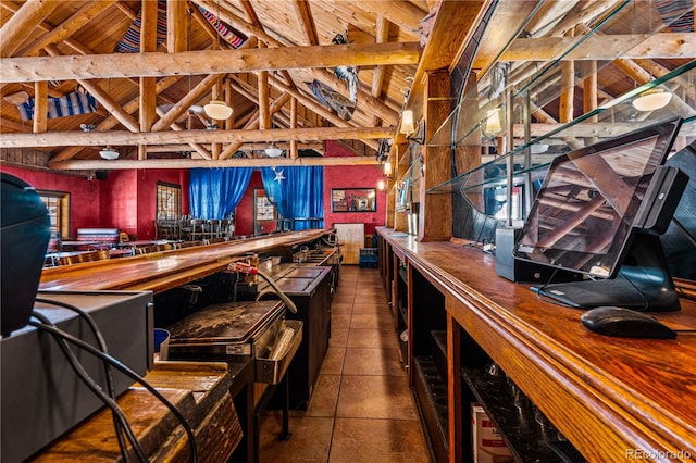 interior space featuring vaulted ceiling with beams and dark tile patterned floors