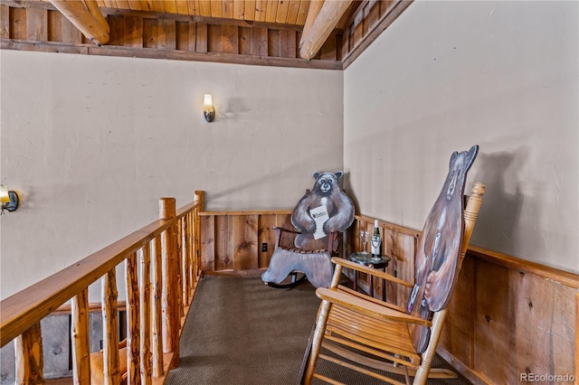 sitting room featuring carpet floors, beamed ceiling, and wooden walls