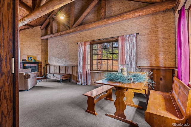 dining space featuring carpet floors, wood walls, beam ceiling, and high vaulted ceiling