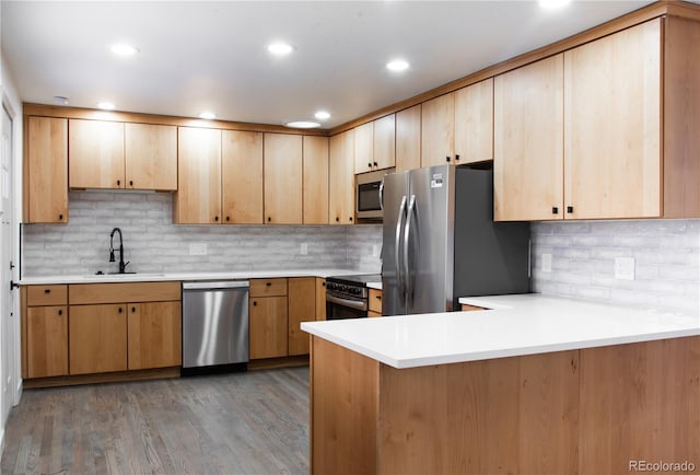 kitchen with dark wood-type flooring, stainless steel appliances, light brown cabinetry, sink, and kitchen peninsula