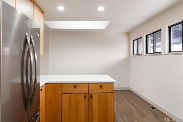 kitchen featuring hardwood / wood-style flooring, a skylight, and stainless steel refrigerator