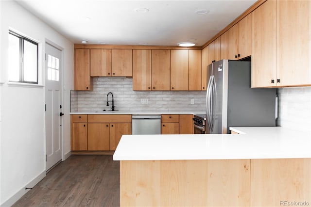 kitchen featuring hardwood / wood-style floors, tasteful backsplash, sink, kitchen peninsula, and stainless steel appliances