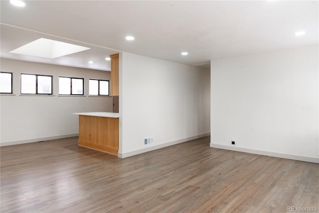 unfurnished room with light hardwood / wood-style floors and a skylight