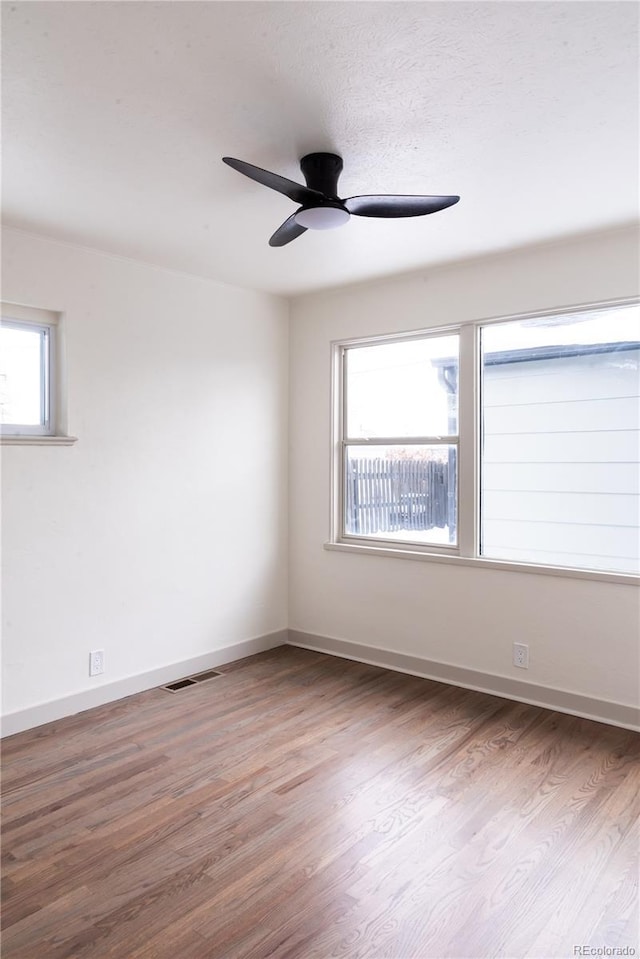 empty room featuring hardwood / wood-style flooring, a healthy amount of sunlight, and ceiling fan