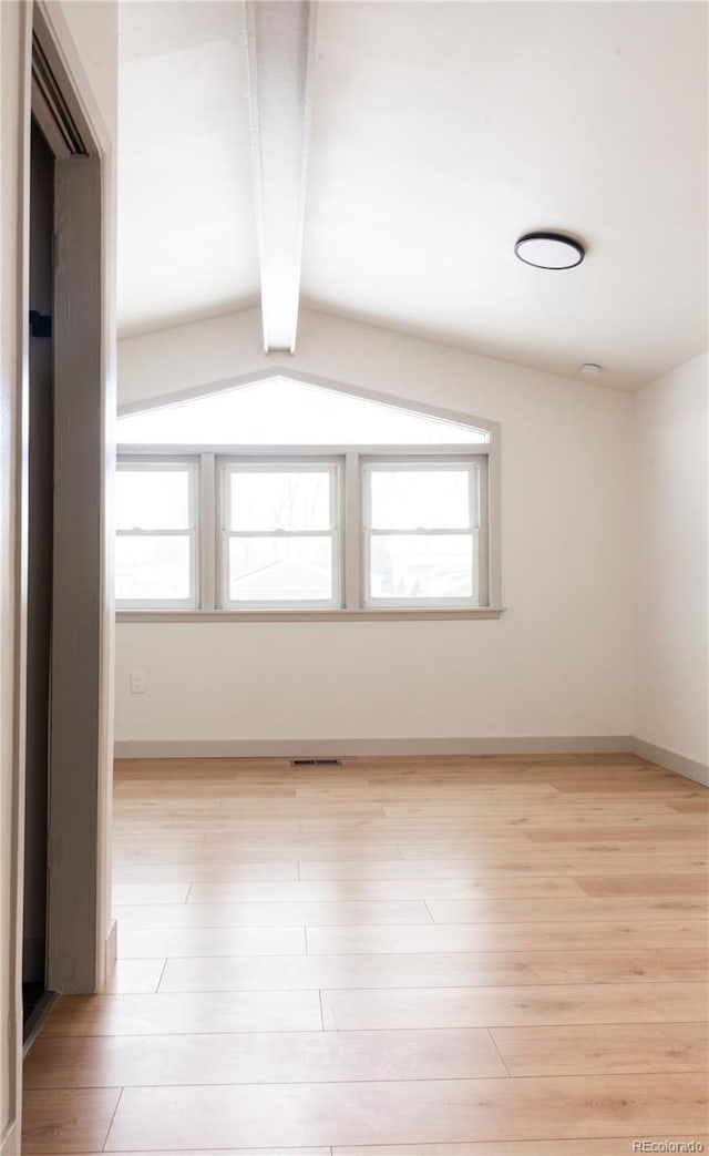 spare room with light hardwood / wood-style flooring and vaulted ceiling with beams