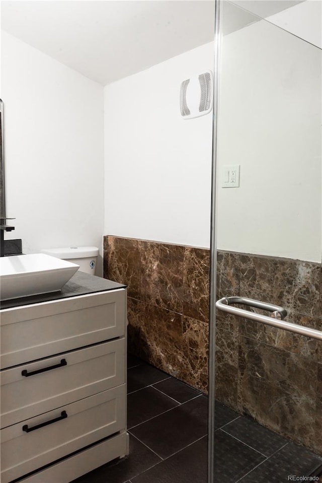 bathroom featuring vanity, toilet, tile walls, and tile patterned floors