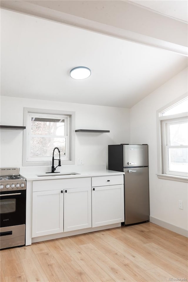 kitchen with sink, light wood-type flooring, white cabinetry, and appliances with stainless steel finishes