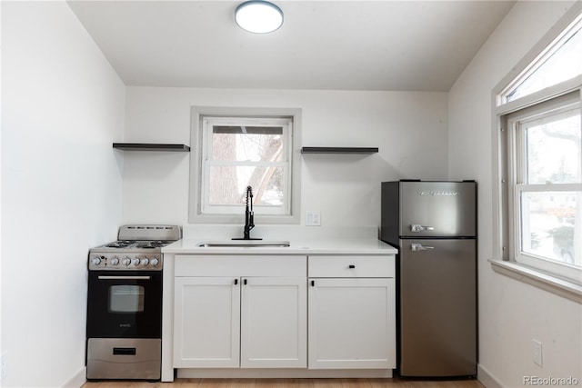 kitchen featuring sink, light hardwood / wood-style floors, white cabinetry, and appliances with stainless steel finishes