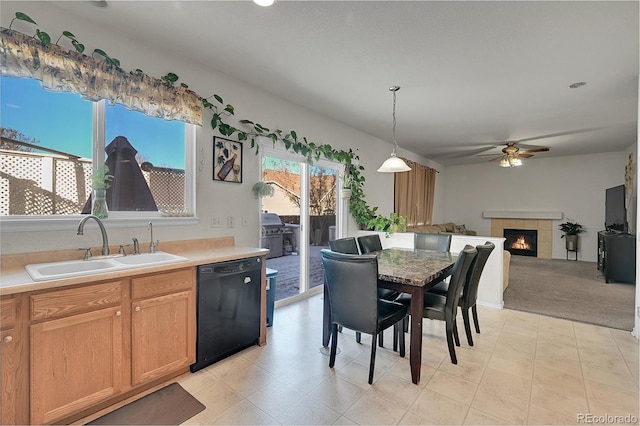 carpeted dining room with a tiled fireplace, sink, and ceiling fan