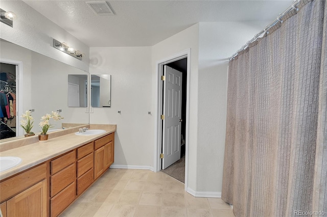 bathroom with a shower with curtain, vanity, and a textured ceiling