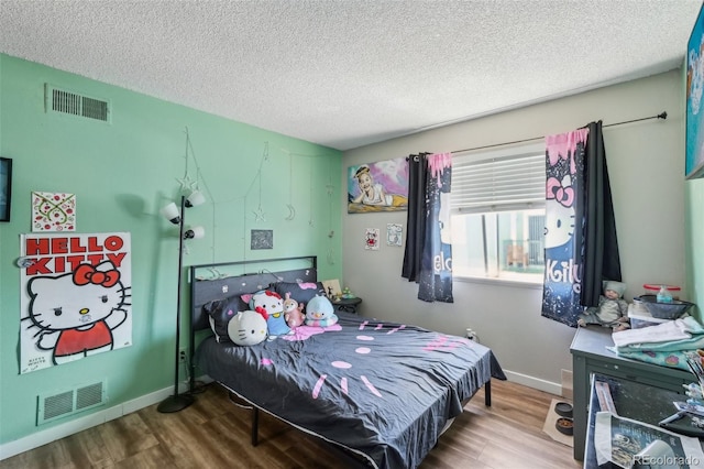 bedroom featuring wood finished floors, a textured ceiling, and baseboards