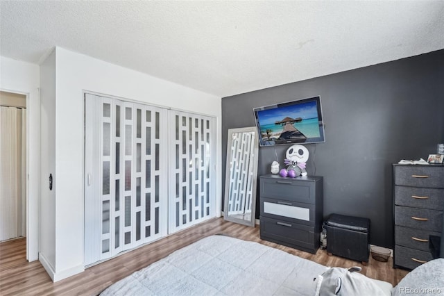 bedroom featuring wood finished floors, a textured ceiling, and baseboards