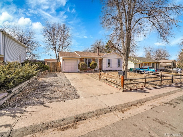 single story home featuring a garage, concrete driveway, and a fenced front yard