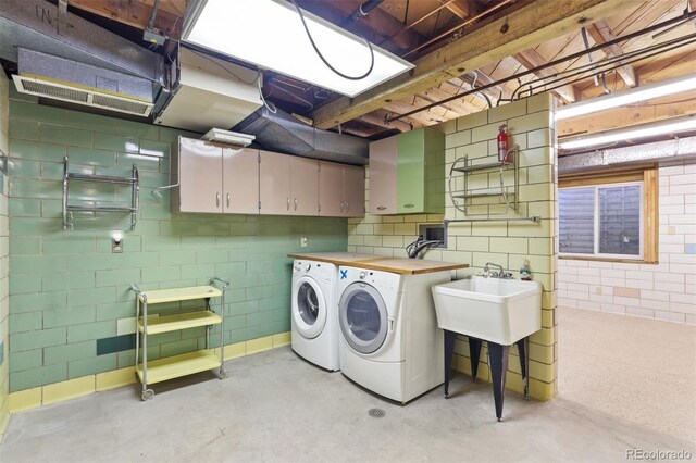 washroom featuring cabinets, sink, and washing machine and clothes dryer