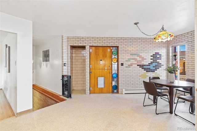 dining room featuring carpet floors, brick wall, and a baseboard heating unit