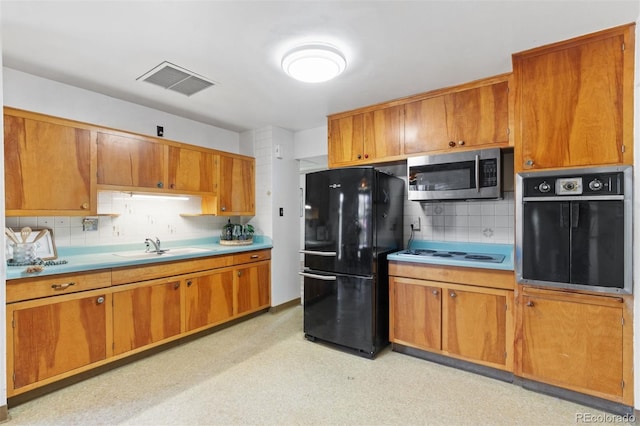 kitchen featuring sink, white electric cooktop, oven, decorative backsplash, and black refrigerator