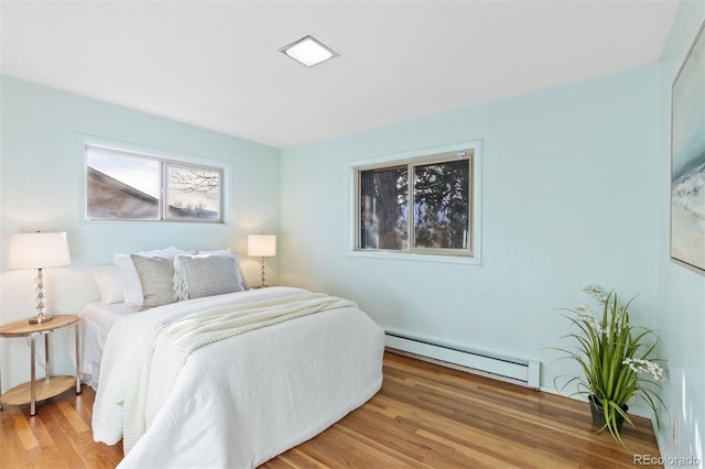 bedroom with hardwood / wood-style floors and baseboard heating