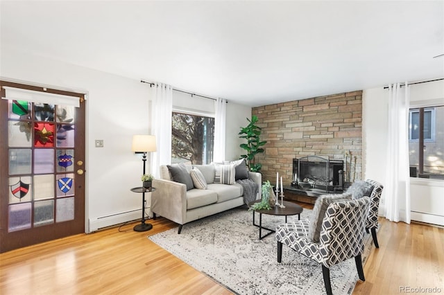 living room featuring baseboard heating, a fireplace, and hardwood / wood-style flooring