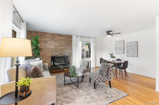 living room with a stone fireplace, ceiling fan, and hardwood / wood-style floors