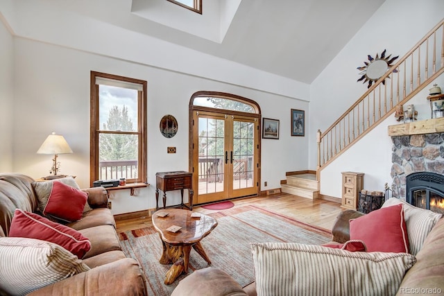 living room featuring light wood-type flooring, a wealth of natural light, a fireplace, and high vaulted ceiling