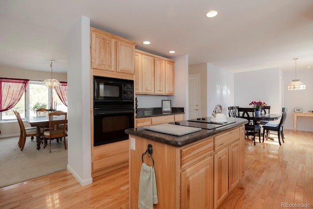 kitchen featuring light brown cabinets, light hardwood / wood-style floors, decorative light fixtures, a kitchen island, and black appliances