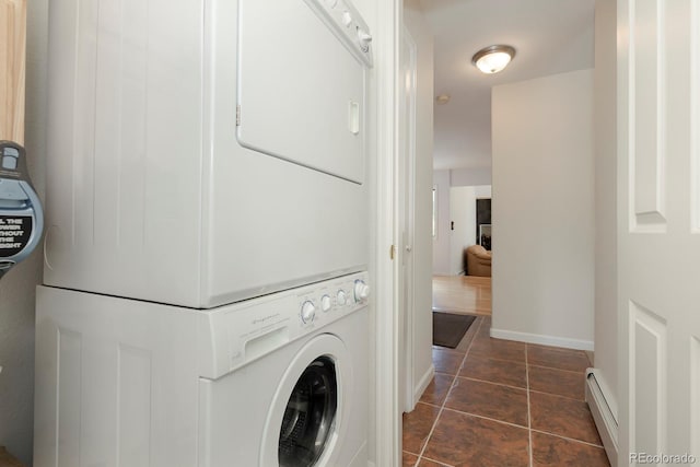 laundry room featuring dark tile patterned flooring, stacked washer / dryer, and a baseboard heating unit