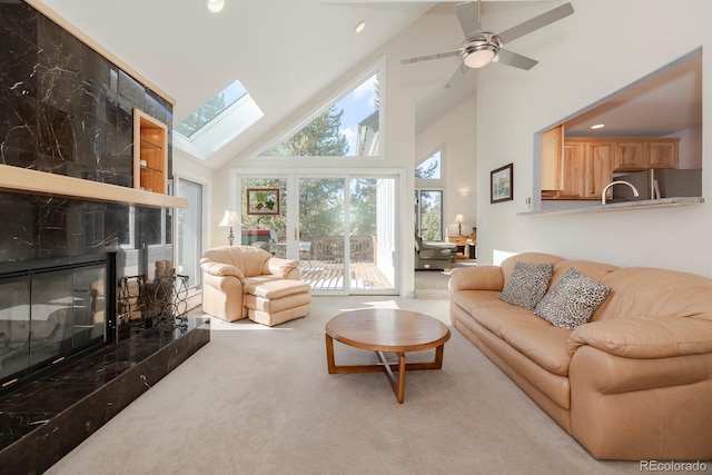 carpeted living area with high vaulted ceiling, a ceiling fan, recessed lighting, a skylight, and a premium fireplace