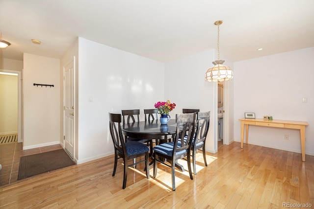 dining space with baseboards and light wood-type flooring
