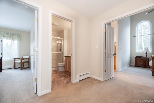 corridor featuring light colored carpet, a healthy amount of sunlight, a baseboard heating unit, and baseboards