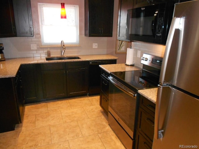 kitchen featuring black appliances, sink, hanging light fixtures, tasteful backsplash, and light stone counters