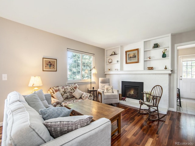 living room with a brick fireplace, dark hardwood / wood-style floors, and a wealth of natural light