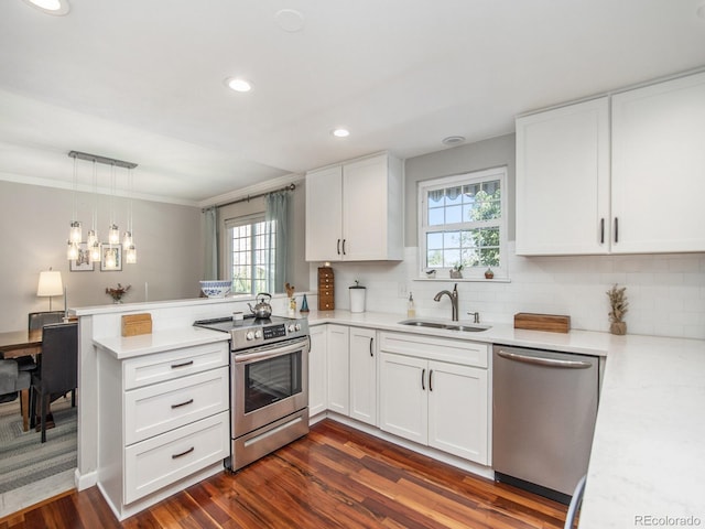 kitchen featuring stainless steel appliances, kitchen peninsula, white cabinets, and a wealth of natural light