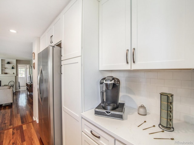 kitchen featuring stainless steel refrigerator, dark hardwood / wood-style floors, decorative backsplash, and white cabinetry