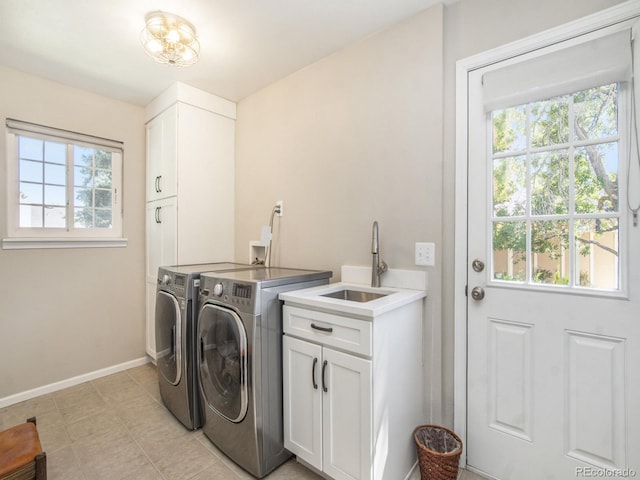 clothes washing area featuring independent washer and dryer, sink, and cabinets