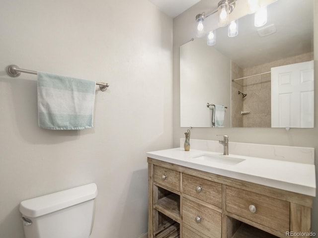 bathroom with vanity, tiled shower, and toilet