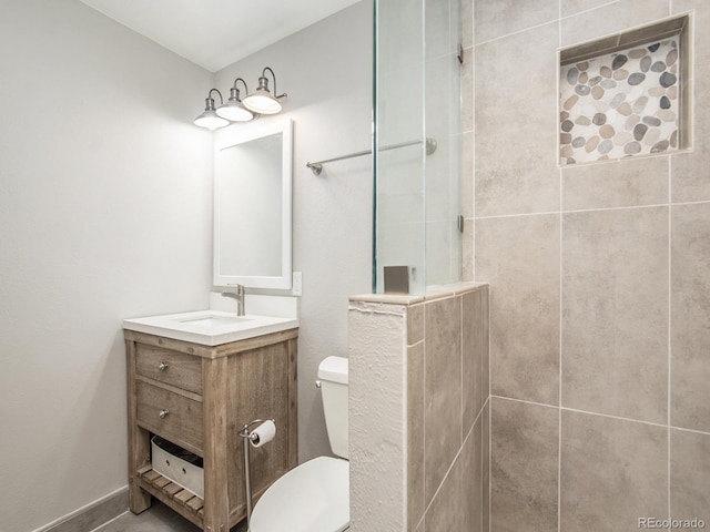 bathroom featuring vanity, tiled shower, and toilet