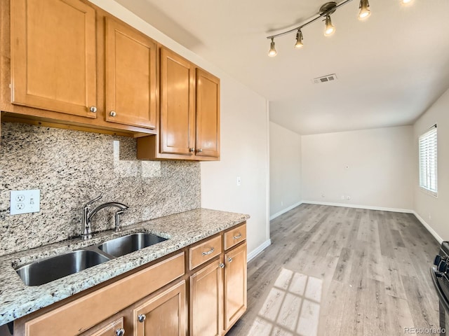 kitchen featuring light wood-type flooring, sink, tasteful backsplash, and light stone countertops