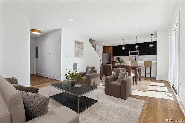 living area featuring recessed lighting, light wood-style floors, and visible vents