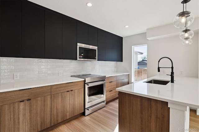 kitchen with a sink, light countertops, appliances with stainless steel finishes, modern cabinets, and dark cabinets