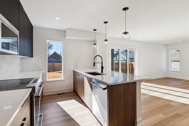 kitchen featuring a sink, modern cabinets, appliances with stainless steel finishes, and light wood-style flooring