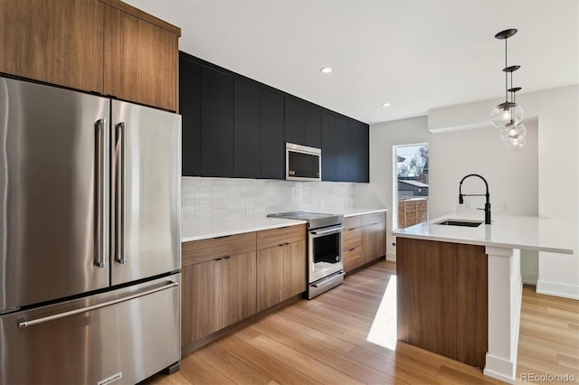 kitchen featuring light wood-type flooring, a sink, backsplash, appliances with stainless steel finishes, and light countertops