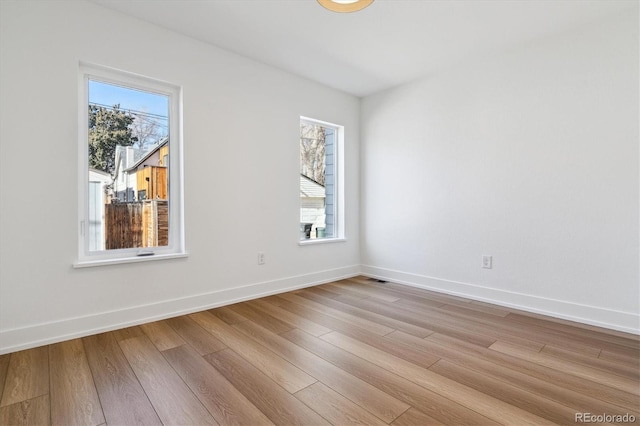 spare room with a healthy amount of sunlight, baseboards, and light wood-style floors