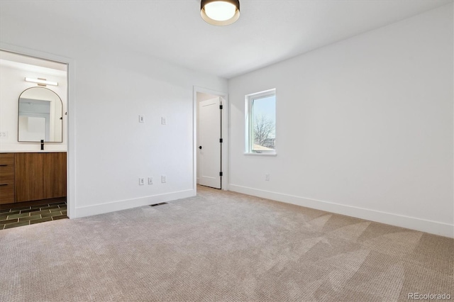 unfurnished bedroom featuring visible vents, a sink, connected bathroom, carpet, and baseboards