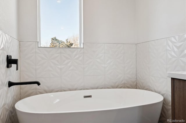 bathroom with vanity, tile walls, and a freestanding tub