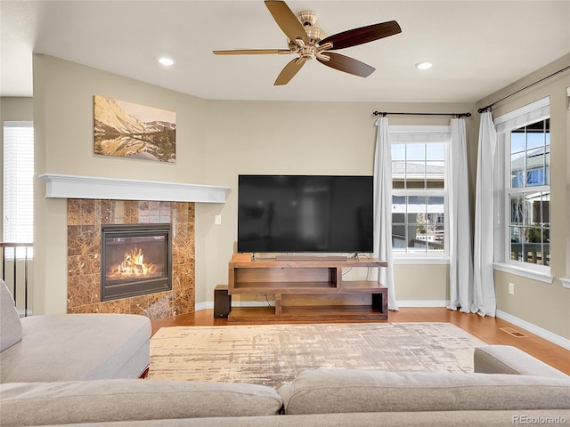 living area featuring recessed lighting, a premium fireplace, wood finished floors, visible vents, and baseboards