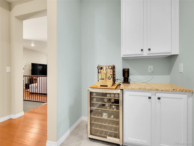 bar featuring a dry bar, beverage cooler, baseboards, and light wood-style flooring